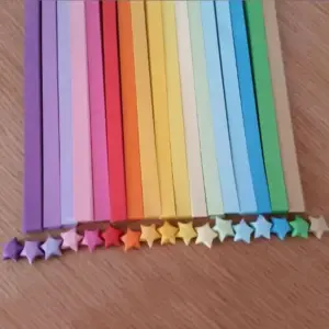 Bunte Papierstreifen in vielen Farben, davor eine Reihe gefalteter Sterne