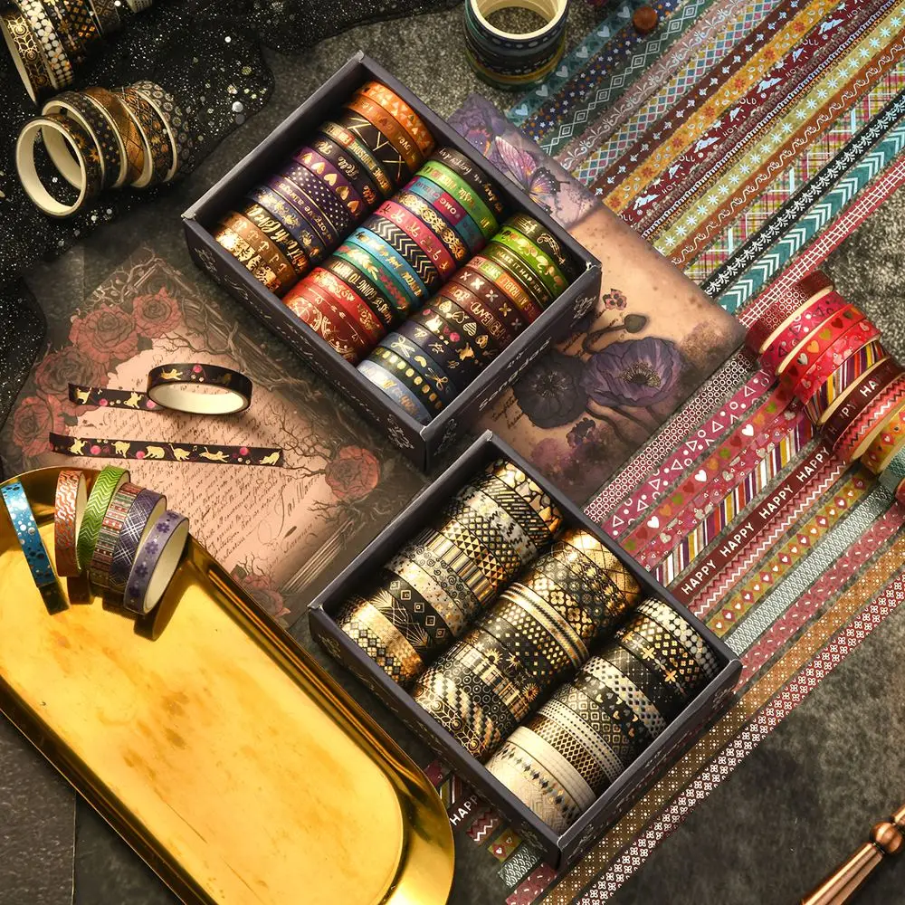 Washi-Tape-Set mit goldverzierten Mustern in dunkler Box zwischen Deko
