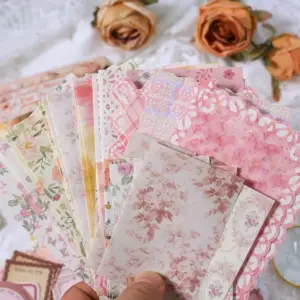 Florale Scrapbooking-Papiere in Rosa mit Spitzenrand und Blütenmotiven auf weißem Stoff